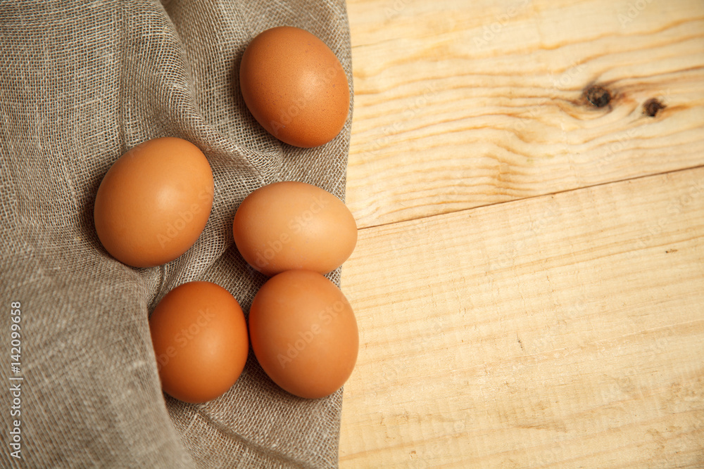 Raw organic brown eggs over linen napkin and rustic wooden background Raw organic brown eggs over linen napkin and rustic wooden background