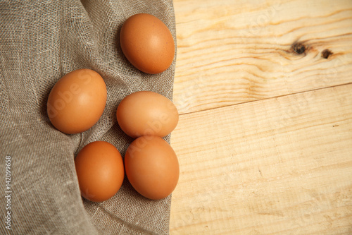 Raw organic brown eggs over linen napkin and rustic wooden background