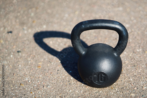 Black Kettlebell isolated on asphalt background.