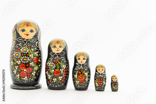 Beautiful black matryoshka dolls with white, green and red painting in front of light background photo
