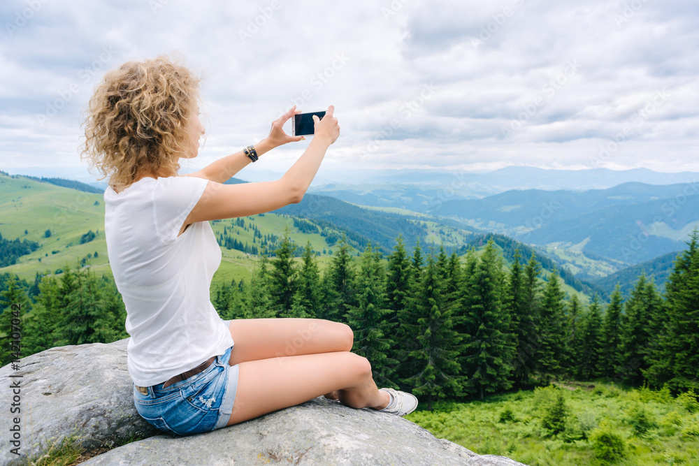 Beautiful woman hiker taking photo with cellphone on mountain top Beautiful woman hiker taking photo with cellphone on mountain top