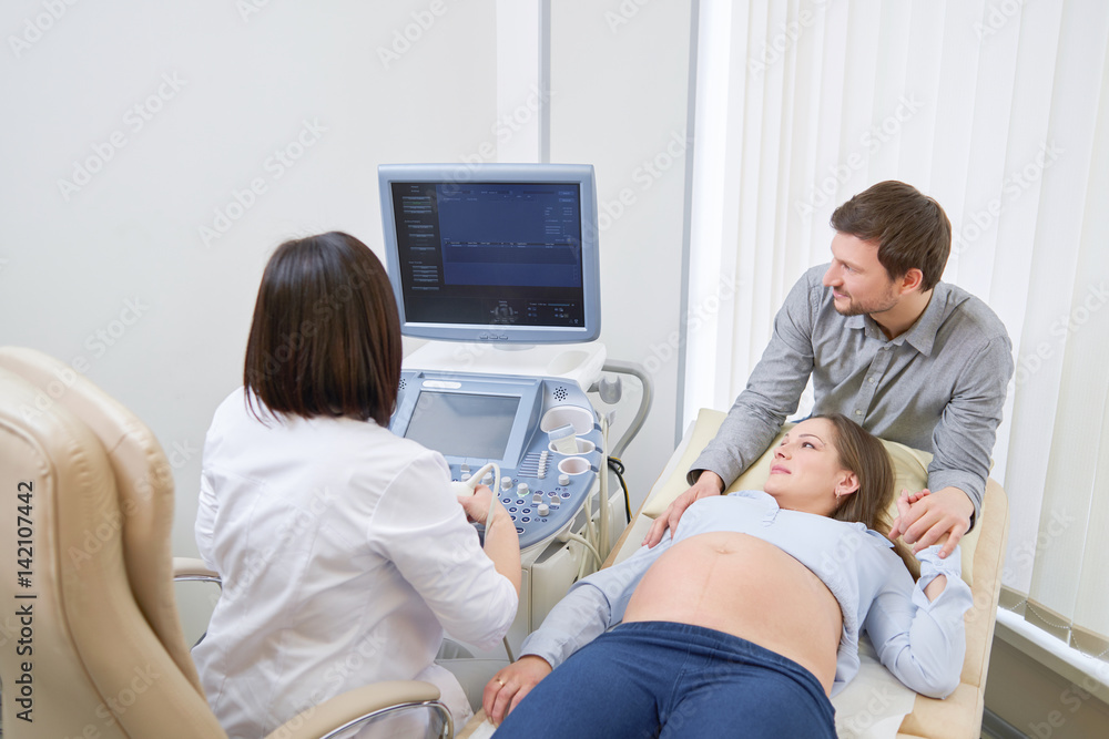 Loving couple attending doctor for pregnancy ultra sound procedu Loving couple attending doctor for pregnancy ultra sound procedu