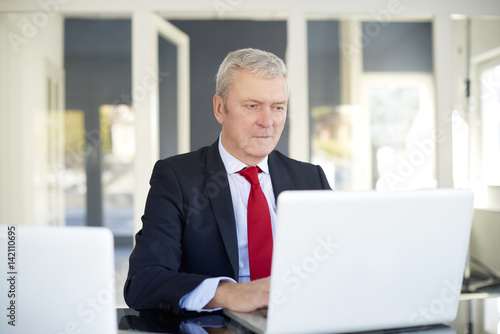 Senior businessman in the office. Shot of a financial managing director working on laptop and analysing financial data.