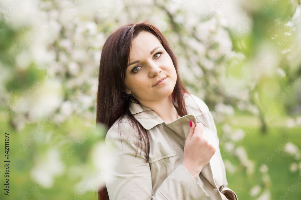 beautiful young brunette woman standing near the blossoming apple tree on a warm spring day beautiful young brunette woman standing near the blossoming apple tree on a warm spring day