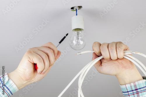 Man with screwdriver and wire near to the bulb
