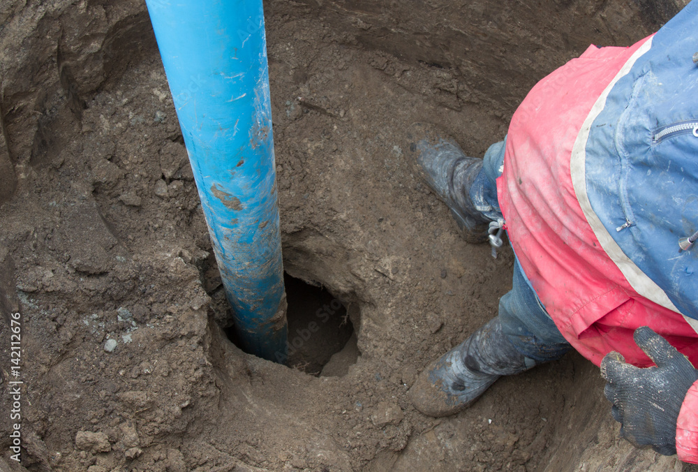 A worker stands near the blue pipe that sticks out from the Earth A worker stands near the blue pipe that sticks out from the Earth