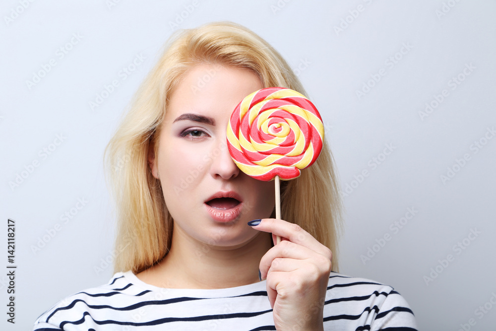 Young beautiful woman with lollipop on grey background