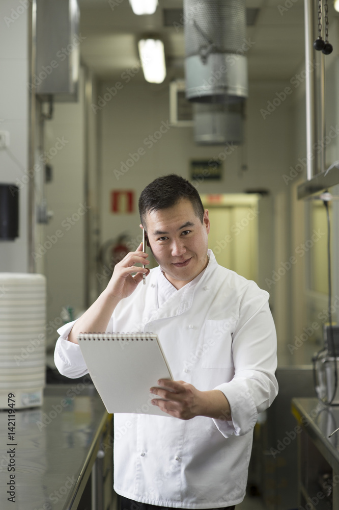 Chinese cook speaks with smartphone and notebook Chinese cook speaks with smartphone and notebook