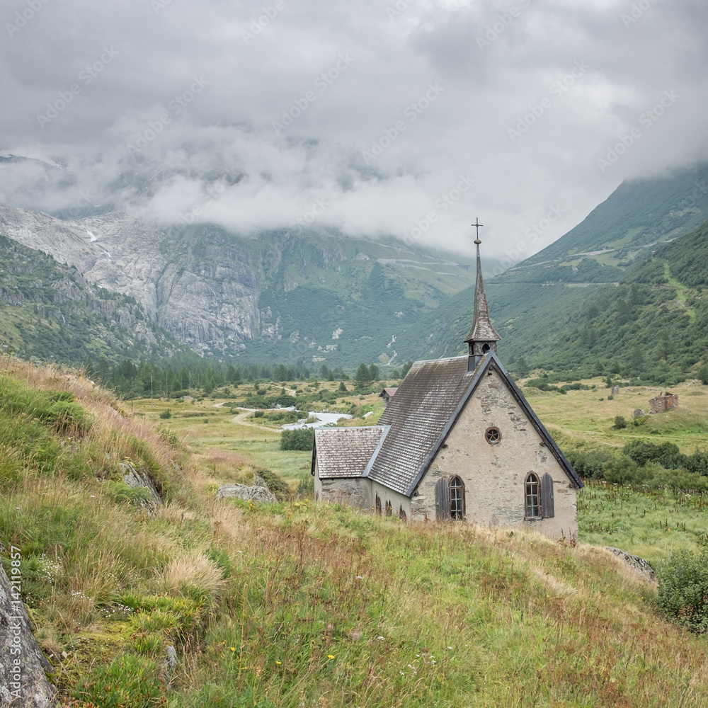 View on the quaint church of Gletsch with misty mountains in the background, Gletsch, Switzerland.