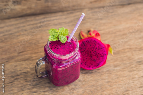 Smoothies of a red organic dragon fruit on an old wooden background photo