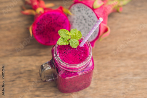 Smoothies of a red organic dragon fruit on an old wooden background photo