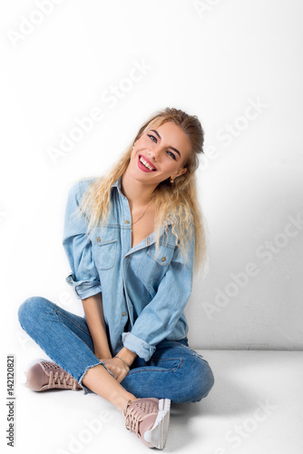 Beautiful girl sits and smiles blonde blue eyes