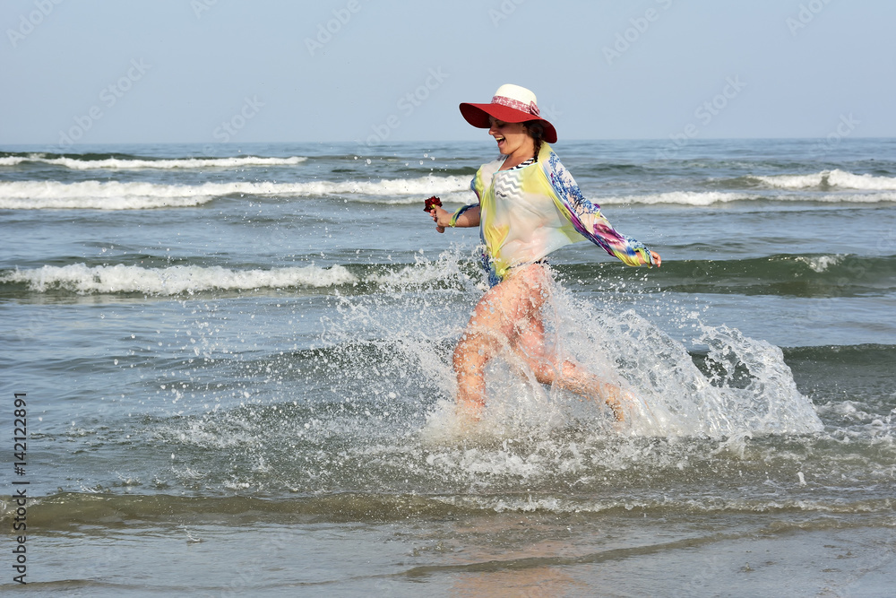 Young woman hight speed running into sea with splashes