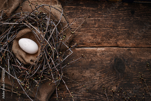 One big egg in the nest with spring branches, on an old wooden table photo