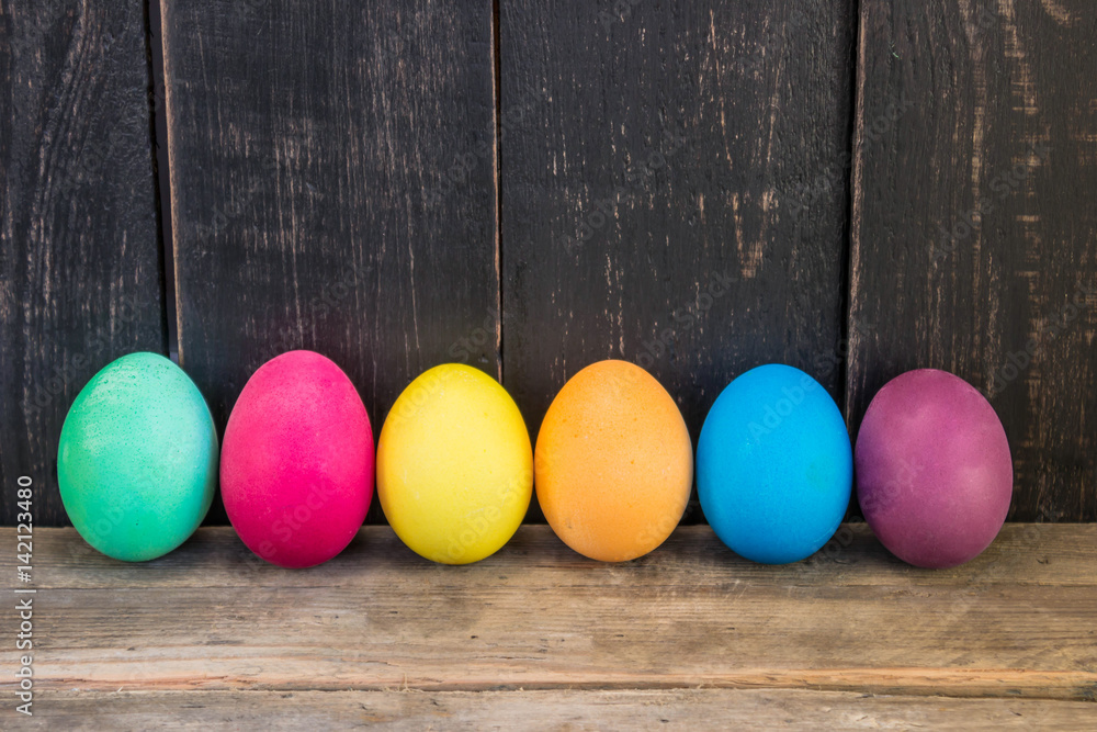 Row of colorful easter eggs on a wooden table Row of colorful easter eggs on a wooden table