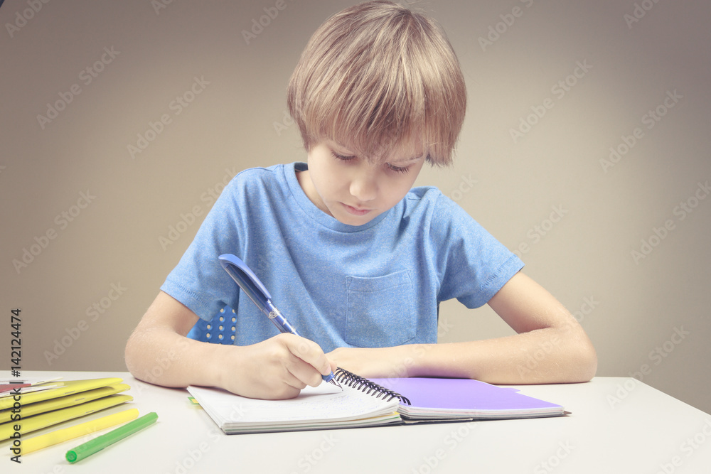 Boy writing on paper notebook. Boy doing his homework exercises Boy writing on paper notebook. Boy doing his homework exercises