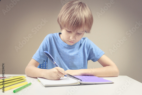 Boy writing on paper notebook. Boy doing his homework exercises