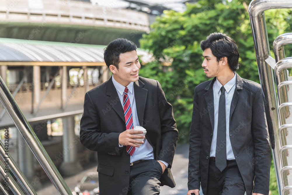 Two young Asian businessman talking to each other outdoor in city Two young Asian businessman talking to each other outdoor in city