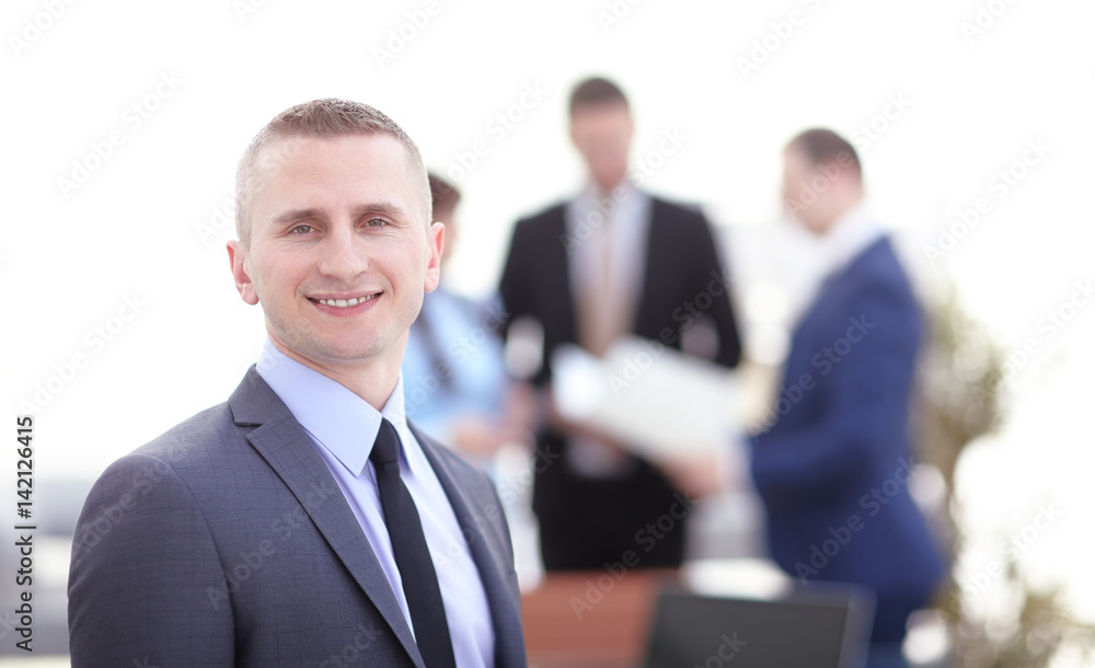 Happy business man working in office with his team in background Happy business man working in office with his team in background