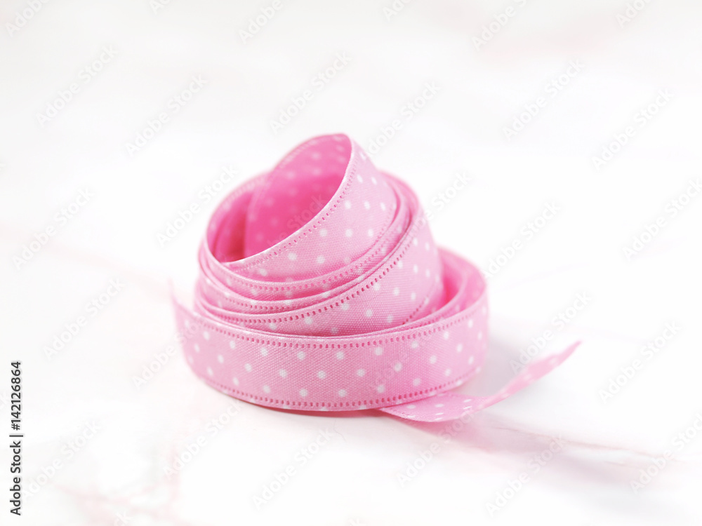 Pink dotted ribbon on light marble background