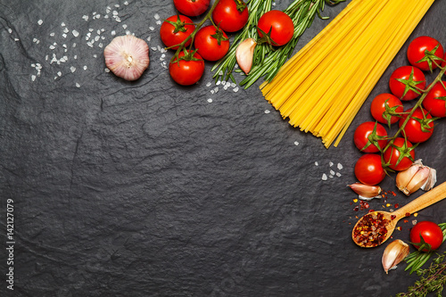 Pasta ingredients. Spaghetti with ingredients sweet basil, tomato, garlic and parmesan cheese on dark background. Top view