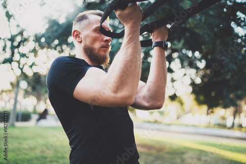Muscular athlete exercising push up outside in sunny park at the morning.Attractive fittness man doing workout exercises outdoors.Blurred background