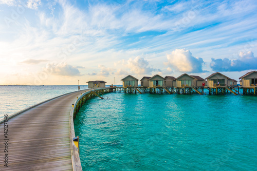 Beautiful sunrise with water villas in tropical Maldives island .