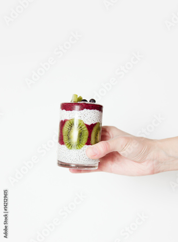 Smoothies in a glass in a hand on a white background with berries and fruits.