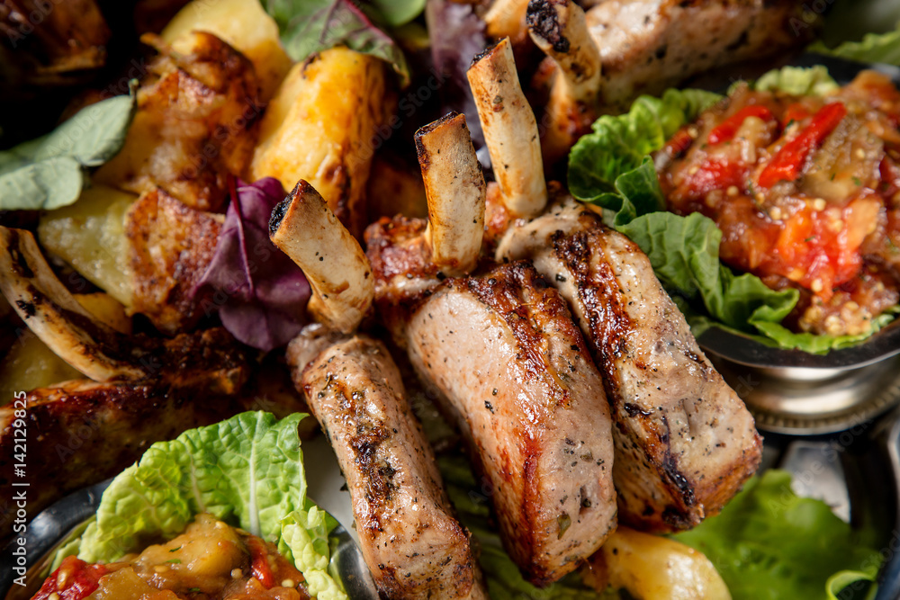 Meat plate with delicious pieces of meat, salad, ribs, grilled vegetables, potatoes and sauce. Close up image with selective focus Meat plate with delicious pieces of meat, salad, ribs, grilled vegetables, potatoes and sauce. Close up image with selective focus