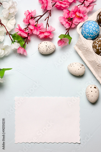 Painted easter eggs and branches of spring sakura closeup on a light blue background with space for congratulation