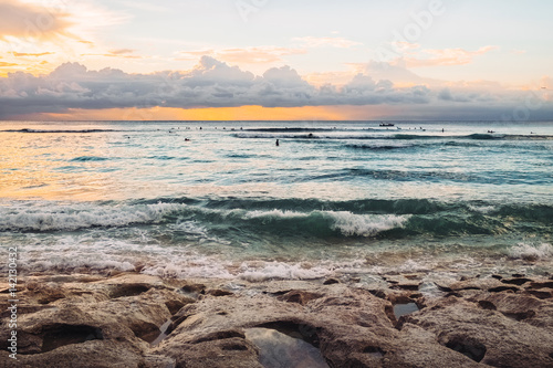 Soft sunset at a fantastic sea beach made of rocks with holes in Bali. Exotic tropical nature of Indonesia sea shore, waves and orange sunset on horizon, outdoor summer nature landscape