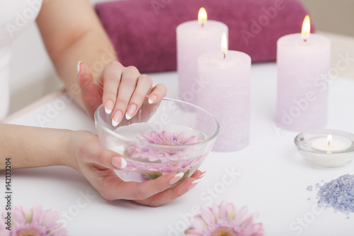 Beautiful manicure with orchid, candle and towel on the white wooden table.