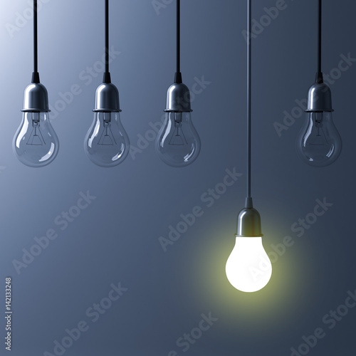 One hanging light bulb glowing different and standing out from unlit incandescent bulbs with reflection on dark cyan background , leadership and different business creative idea concept. 3D rendering. photo