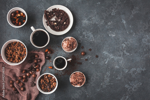 Cups of coffee, chocolate cake, chocolate muesli and chocolate ice cream on dark background. Flat lay, top view, copy space