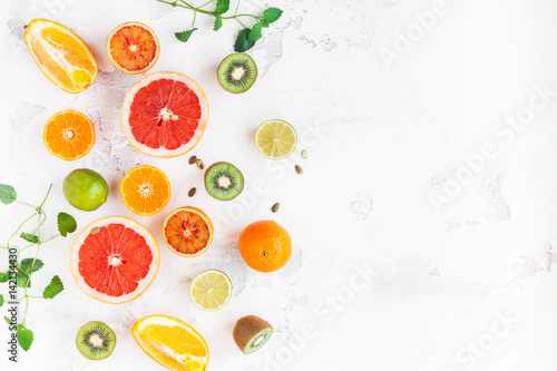 Fruit background. Colorful fresh fruit on white table. Orange  tangerine  lime  kiwi  grapefruit. Flat lay  top view  copy space