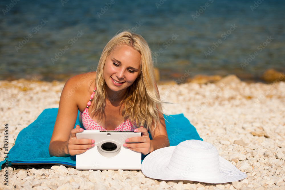 woman surfing internet looking at tablet on the beach