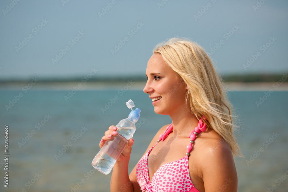 woman drinking water on the beach