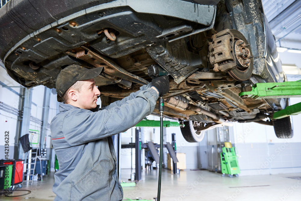 Auto repair service. Mechanic works with car suspension Auto repair service. Mechanic works with car suspension