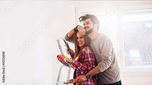 Young cheerful couple choosing color for painting home