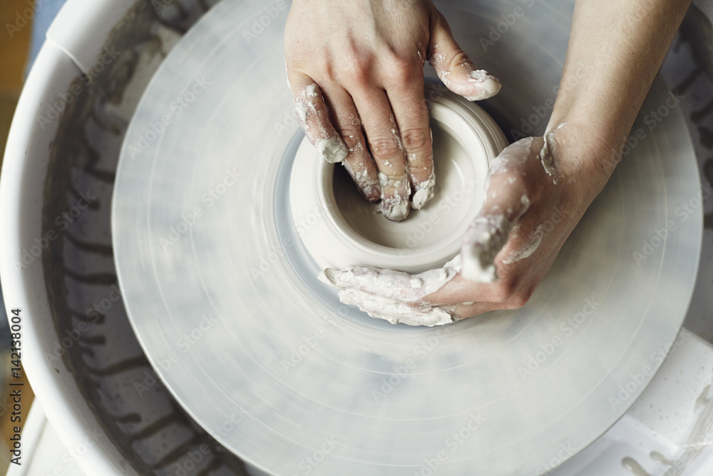 Fototapeta premium Ceramic working process with clay potter's wheel, close-up of woman hands