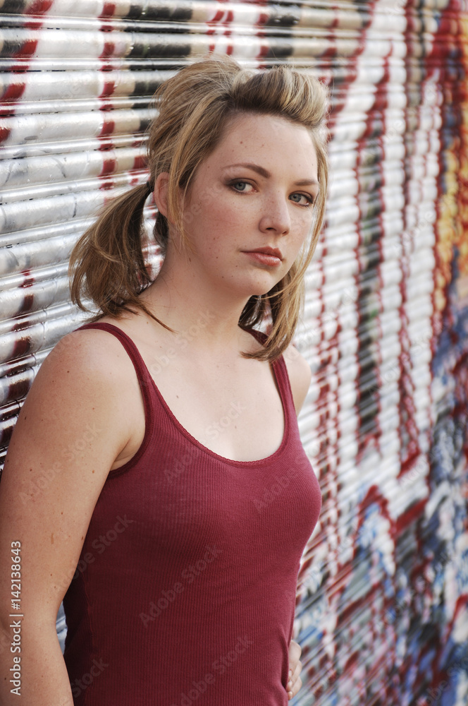 Naklejka premium Cautious Teen Girl in Alley with Graffiti