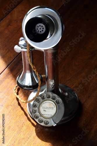 Retro chrome candlestick telephone on wooden desk 