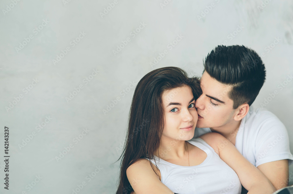 A couple in love sits on a light background. Mutual understanding, love and support. We are happy together. A couple in love sits on a light background. Mutual understanding, love and support. We are happy together.