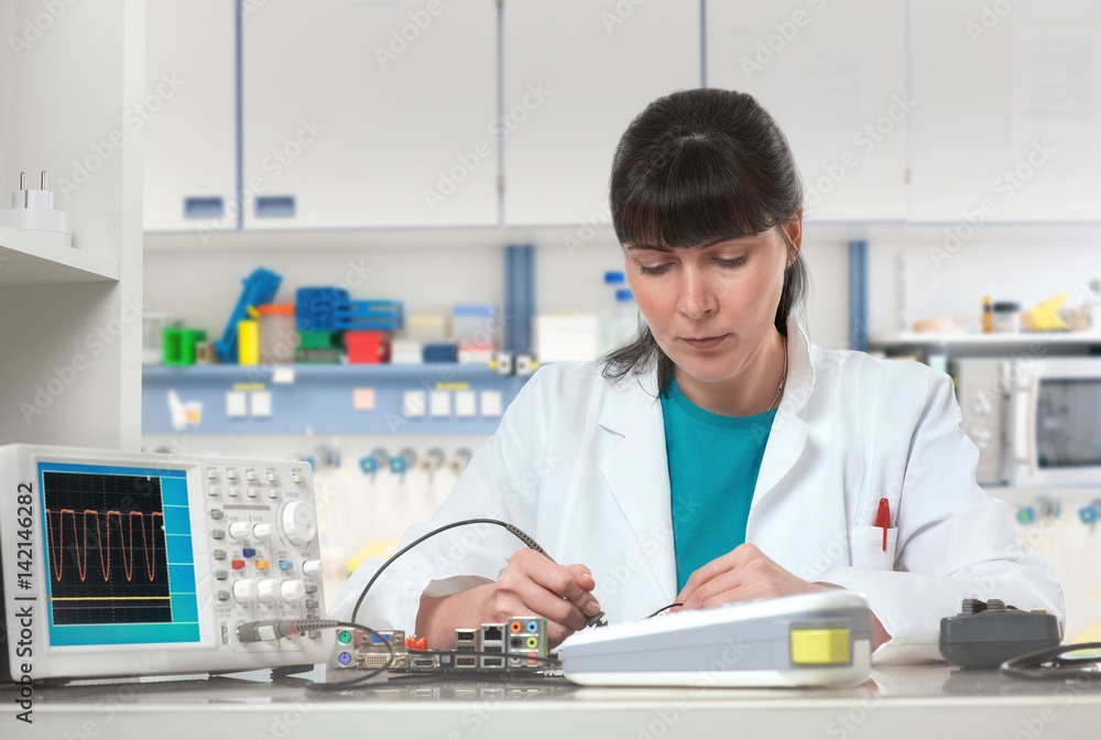 Young female tech or engineer repairs electronic equipment in research facility Young female tech or engineer repairs electronic equipment in research facility