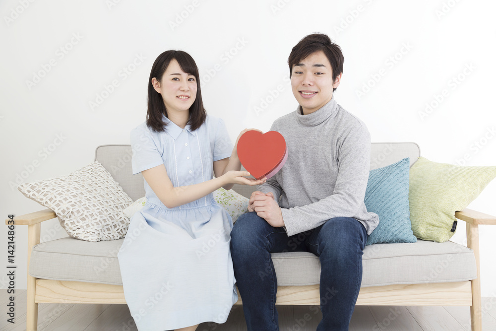 ハートを持つ幸せなカップルイメージ カメラ目線 笑顔 室内ソファーに座る Stock Photo Adobe Stock