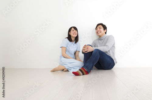 新生活 新居に引越イメージ カップル 男女 床に座って笑顔 シンプル空間