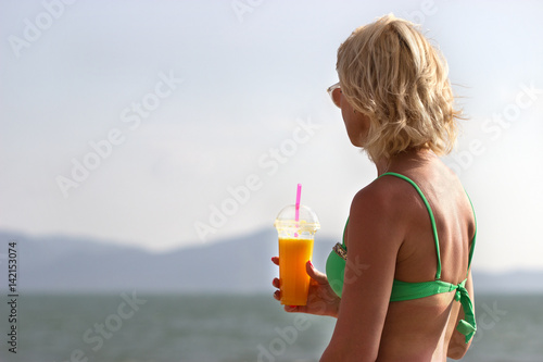Женщина на пляже пьёт свежийнатуральный  сок