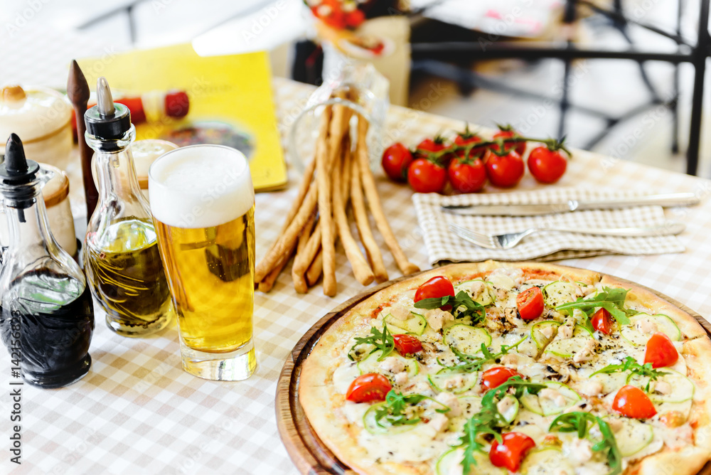 Tasty pizza with glass of beer, on served table