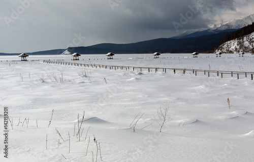 Snow-covered arbors on the shore of winter lake Baikal