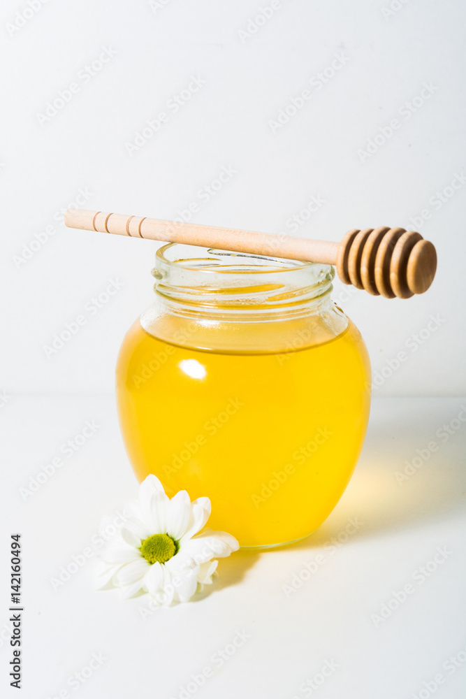 Light honey in the jar with spoon and flower Light honey in the jar with spoon and flower